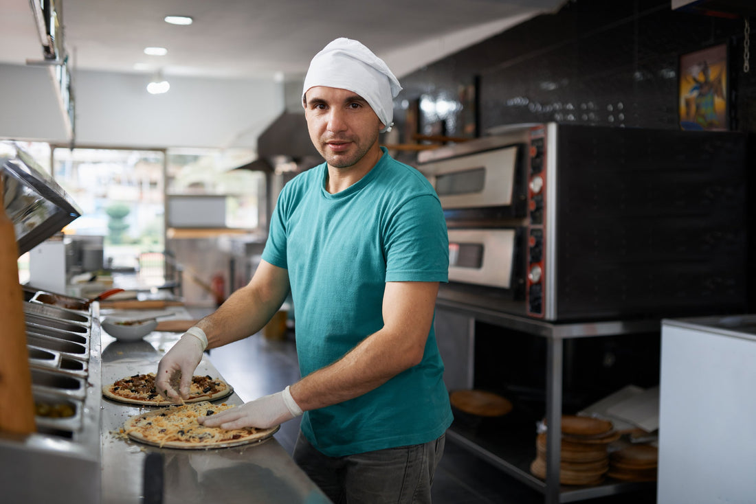 A chef making pizza on a pizza prep fridge